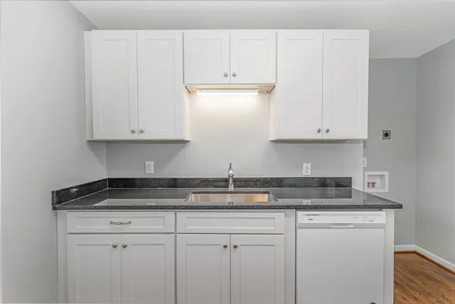 a kitchen with stainless steel appliances granite countertop white cabinets sink and granite counter top