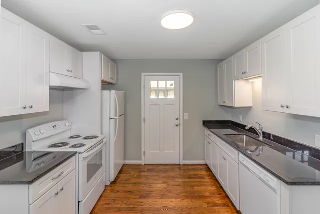 a kitchen with granite countertop a sink stove and refrigerator