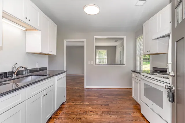 a kitchen with granite countertop a stove sink and cabinets