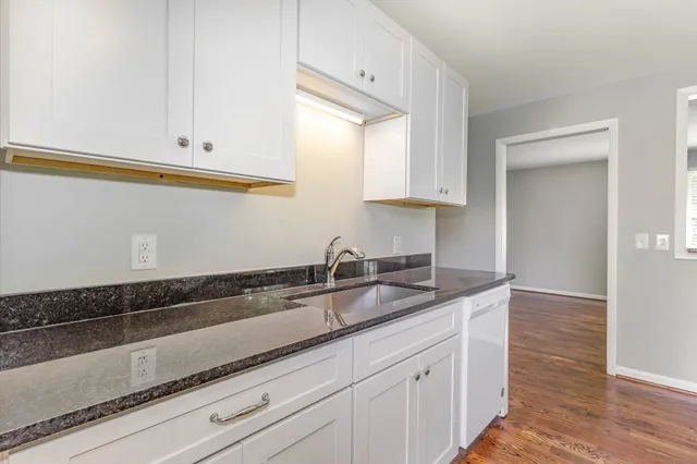 a kitchen with granite countertop white cabinets and a sink