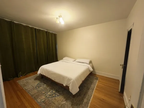 a bed sitting in a spacious bedroom next to a window