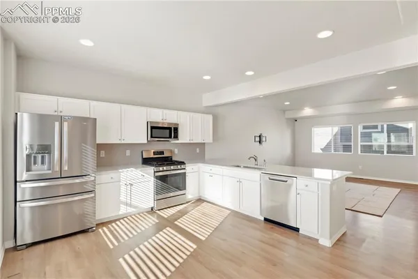 a large white kitchen with stainless steel appliances granite countertop a stove and a sink