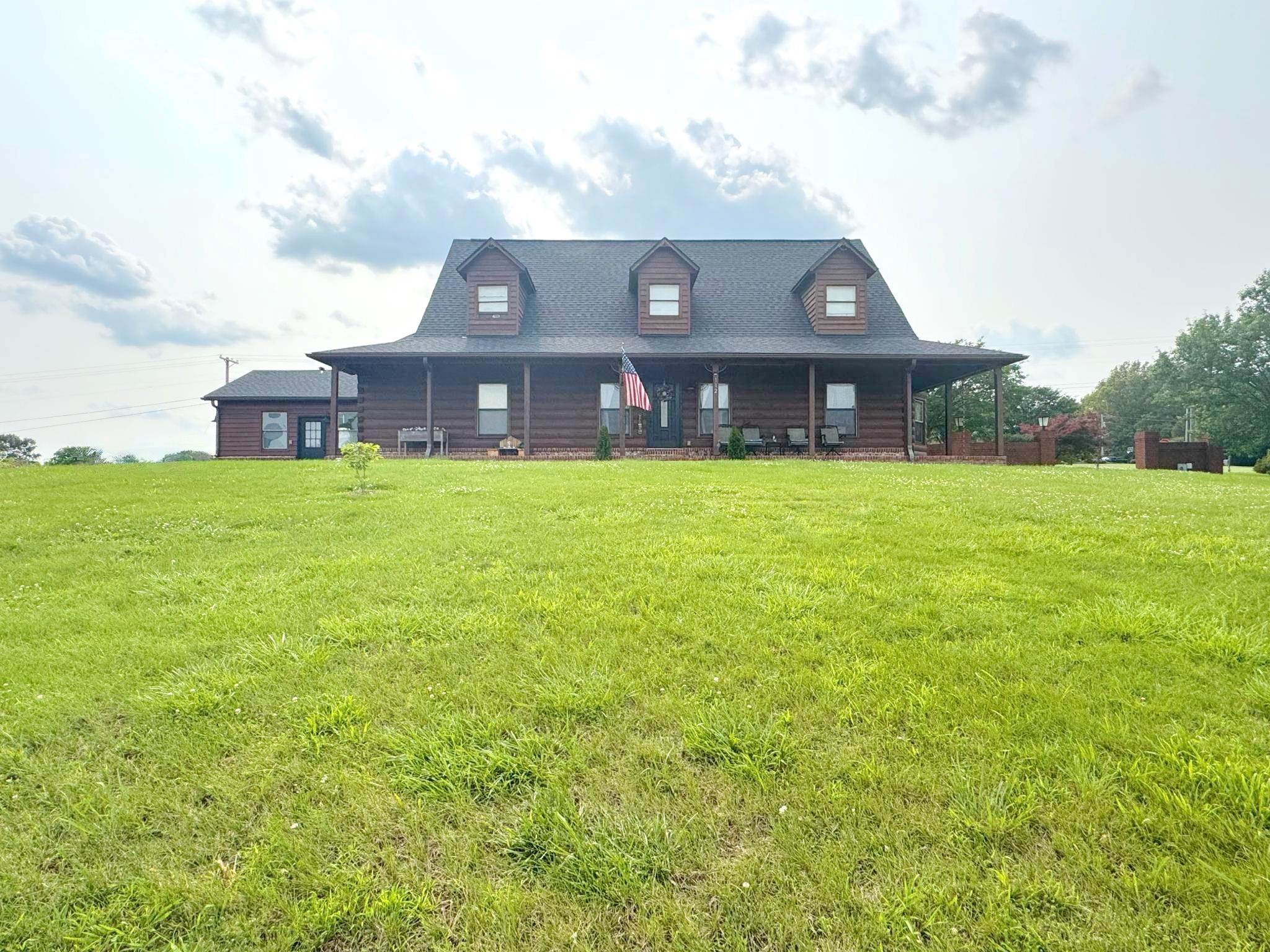 Cabin with a front yard, roof with shingles, and covered porch