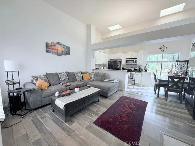 a living room with furniture wooden floor and kitchen view
