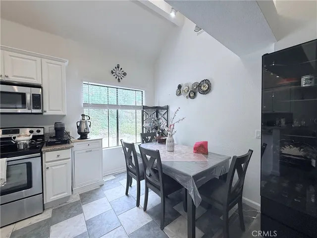 a dining room with stainless steel appliances a table and chairs in it
