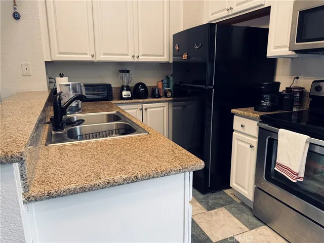 a kitchen with granite countertop a refrigerator stove and sink