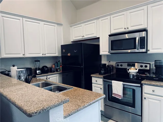 a kitchen with granite countertop a refrigerator stove and microwave
