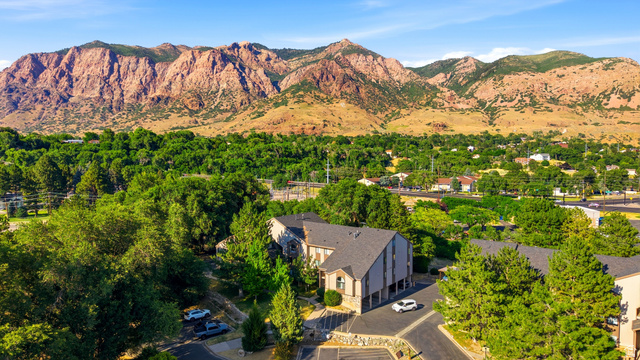 1175 Canyon Road, Unit 86 Ogden, UT 84404 - Photo 29 of 29 Aerial perspective showcasing a multi-level residential building with a dark shingle roof, set among mature green trees
