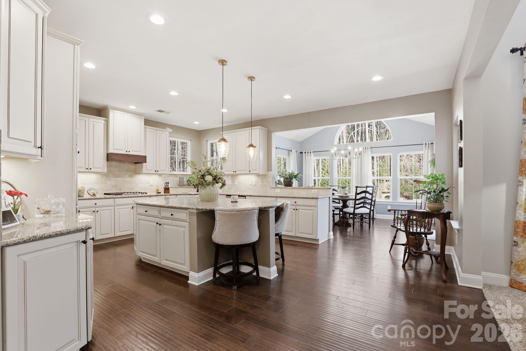 215 Streamwood Road Troutman, NC 28166 - Photo 17 of 48 a kitchen with stainless steel appliances kitchen island granite countertop a table chairs sink and white cabinets