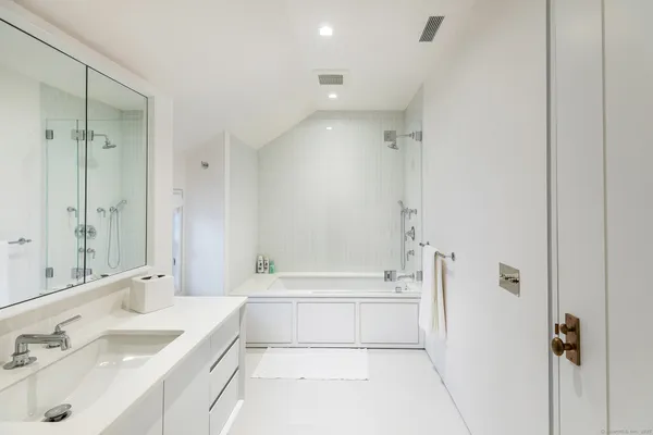 a bathroom with a tub a sink and mirror