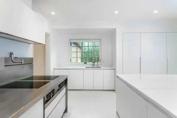 a large kitchen with stainless steel appliances a large counter top a stove a chimney a sink and dishwasher