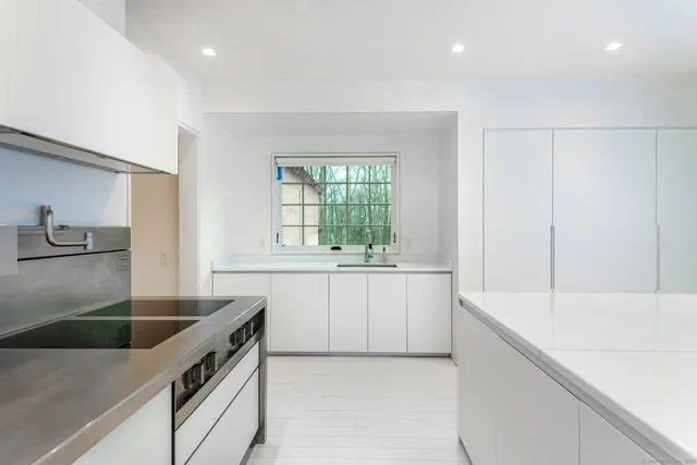 a kitchen with a sink dishwasher a stove and white cabinets with wooden floor