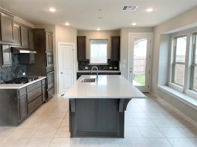 a kitchen with kitchen island granite countertop a sink counter top space a refrigerator and a view of living room