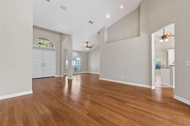 an empty room with wooden floor and windows