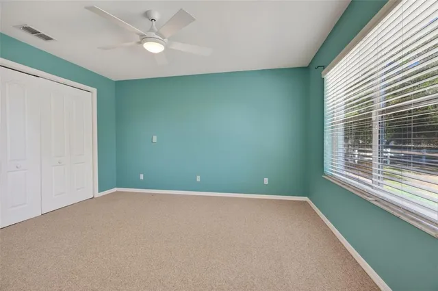an empty room with a window and ceiling fan