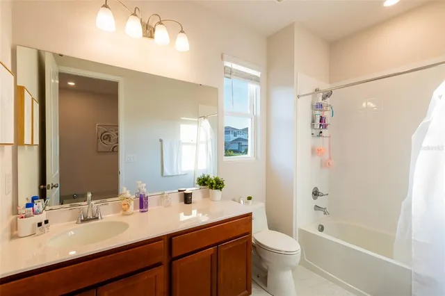 a bathroom with a bathtub shower sink mirror vanity and a toilet