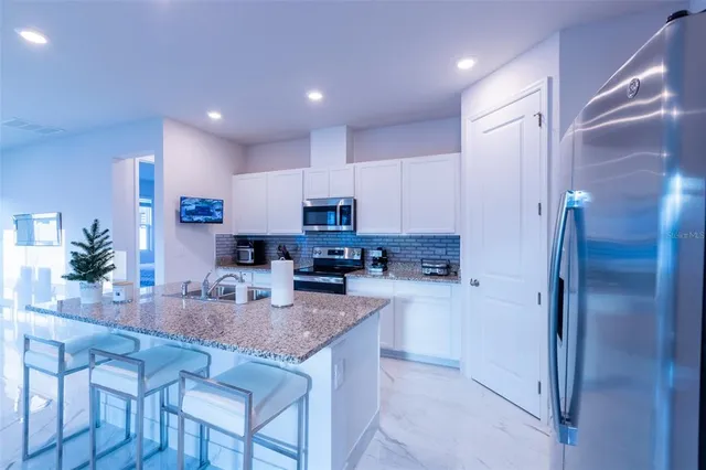 a kitchen with stainless steel appliances granite countertop a refrigerator and a stove top oven