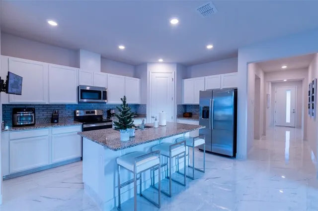 a kitchen with stainless steel appliances granite countertop a refrigerator oven a sink a stove a dining table and chairs