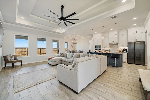 a living room with stainless steel appliances kitchen island granite countertop furniture a rug kitchen view and a chandelier