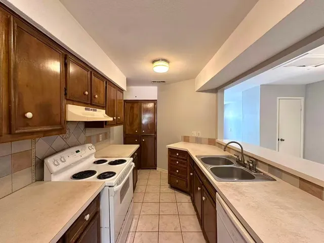 a kitchen that has a sink a stove and a refrigerator