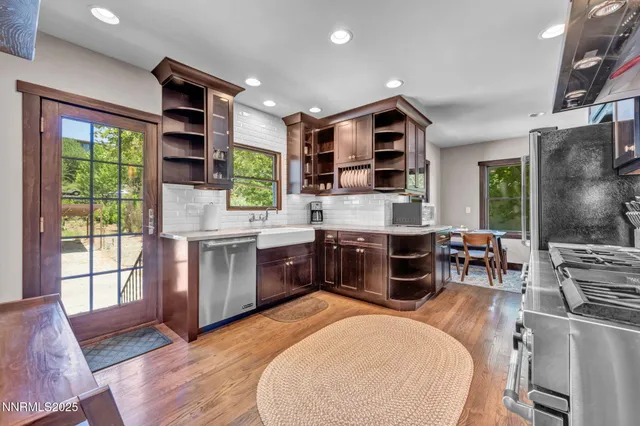 a large kitchen with stainless steel appliances a large counter top a stove and a wooden floors