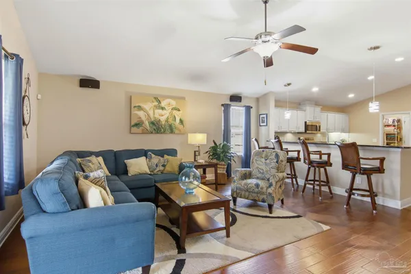 a living room with furniture kitchen view and a chandelier