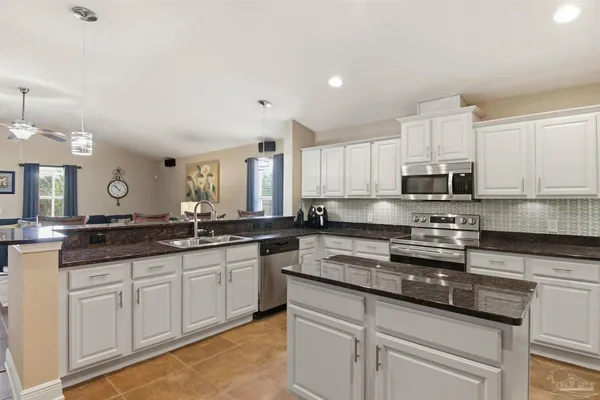 a kitchen with stainless steel appliances granite countertop a stove top oven a sink a counter space and cabinets