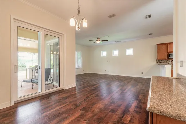 a view of an empty room and kitchen with furniture wooden floor and a ceiling fan