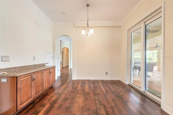 an empty room with a chandelier fan and windows