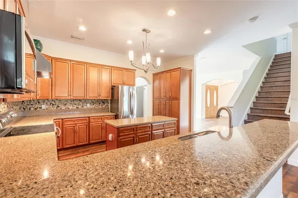 an empty room with wooden floor chandelier fan and windows