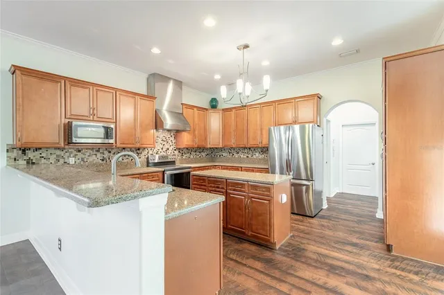 a kitchen with stainless steel appliances granite countertop a refrigerator a sink dishwasher a stove with wooden cabinets and floors