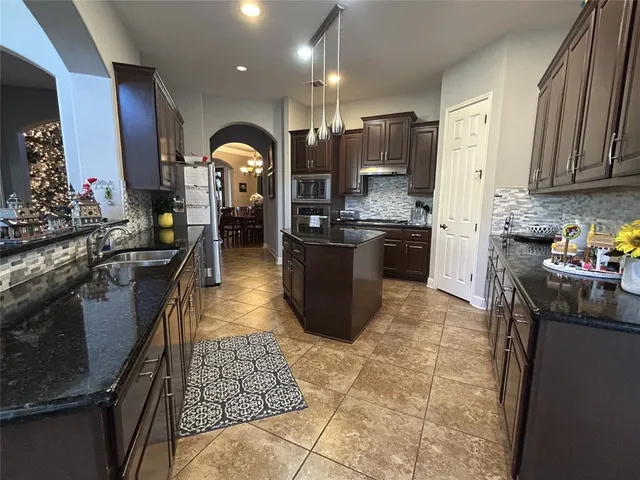 a kitchen with stainless steel appliances granite countertop a sink a stove and a refrigerator