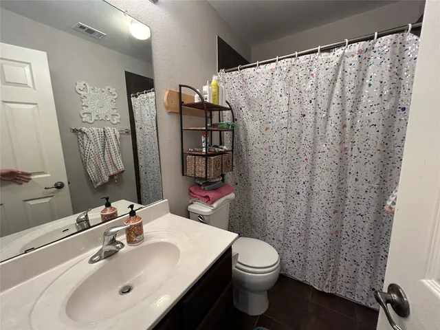 a bathroom with a sink a toilet and shower curtain
