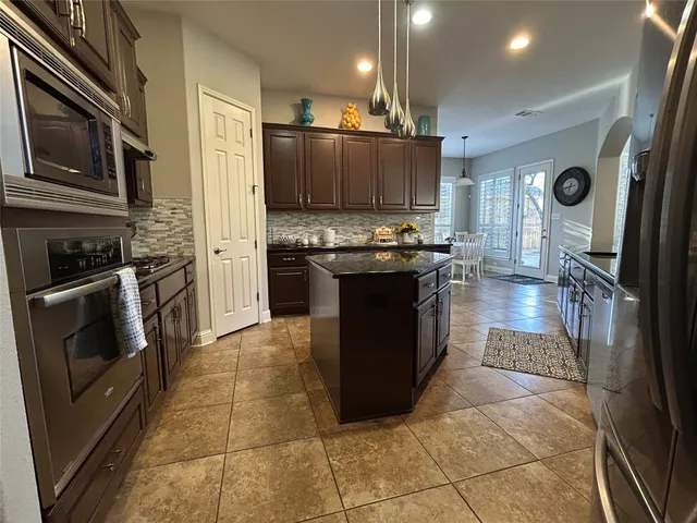 a kitchen with stainless steel appliances granite countertop a stove a sink and a refrigerator