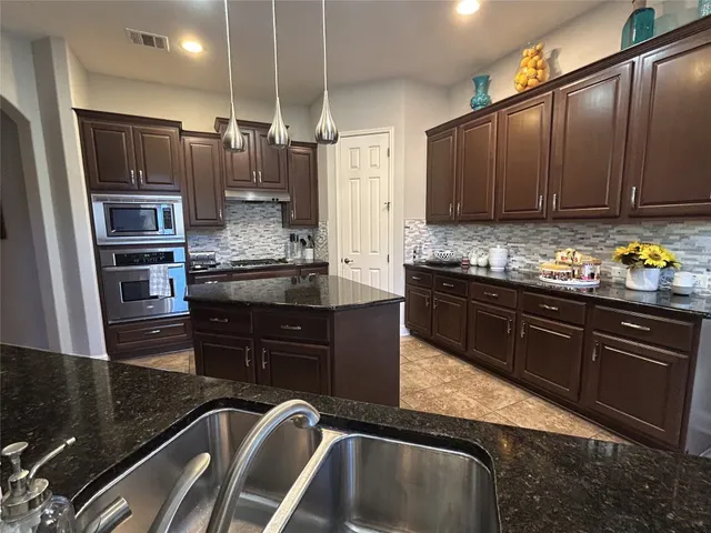 a kitchen with kitchen island granite countertop a sink stainless steel appliances and cabinets
