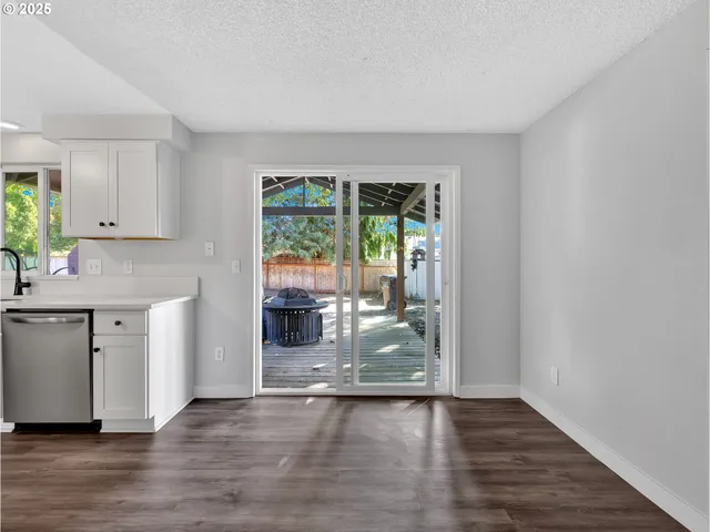 a kitchen with granite countertop a stove a sink and a granite counter tops with white cabinets next to a window