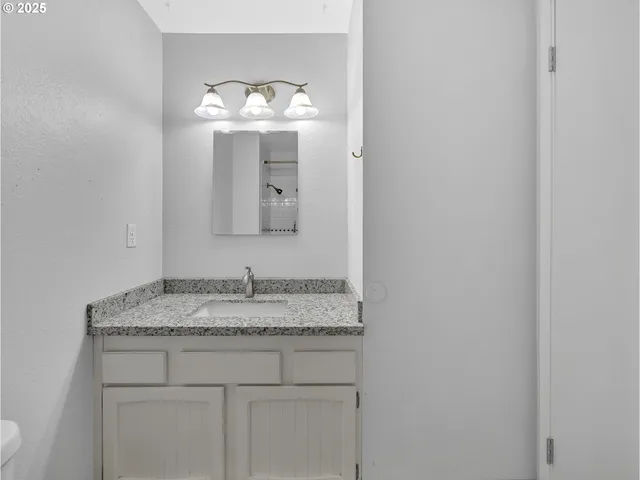 a bathroom with a granite countertop sink and a mirror