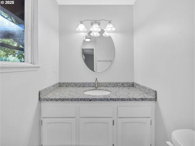 a bathroom with a granite countertop sink a toilet and a mirror