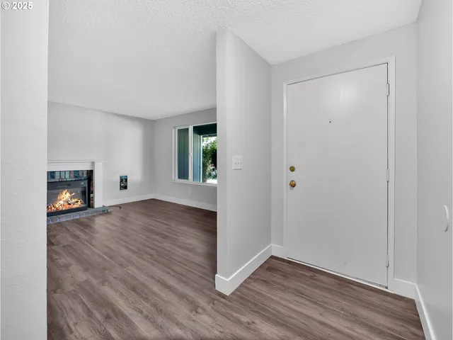 a view of empty room with wooden floor and fireplace