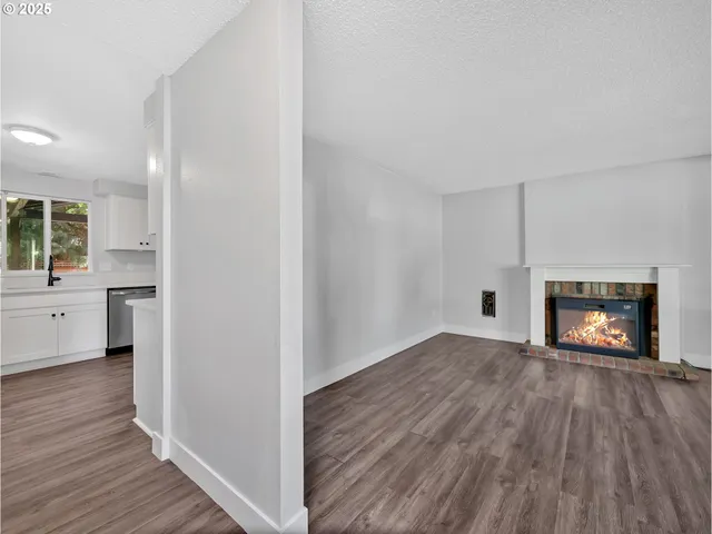 a view of empty room with wooden floor and fireplace