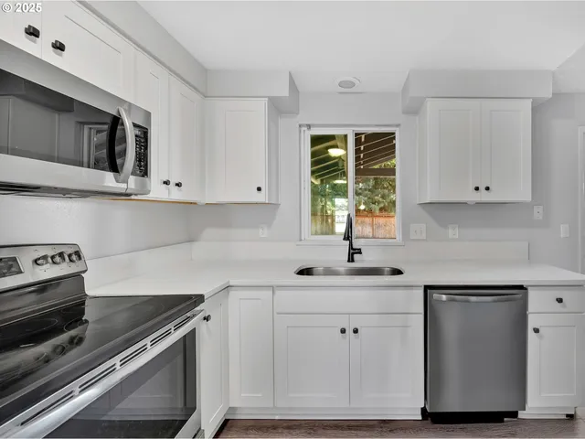 a kitchen with white cabinets and appliances