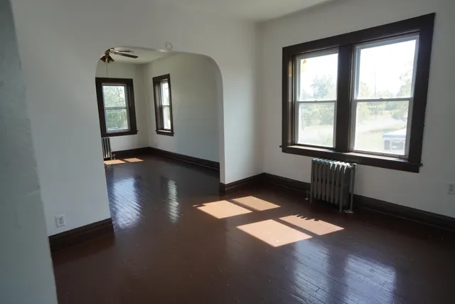 an empty room with wooden floor and windows
