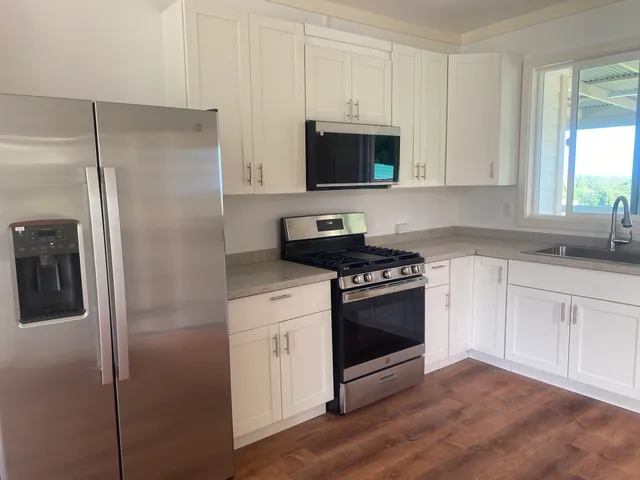 a kitchen with stainless steel appliances granite countertop a refrigerator stove and white cabinets
