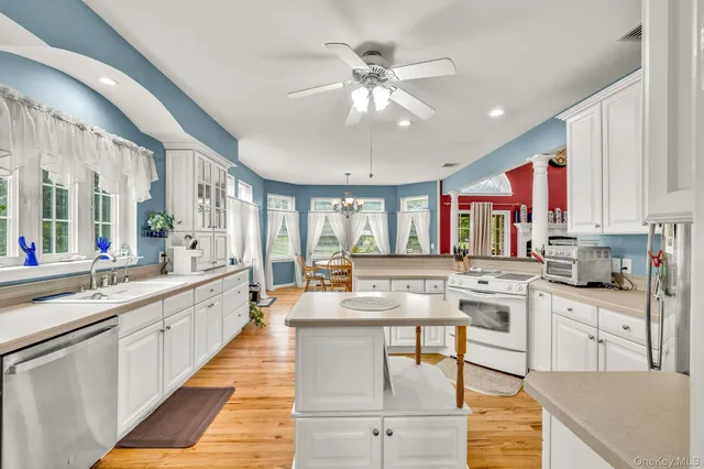 a large white kitchen with lots of counter top space and stainless steel appliances
