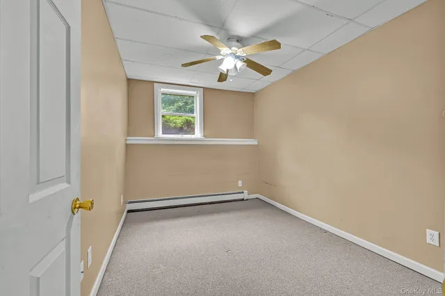 an empty room with a chandelier fan and windows