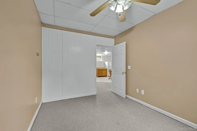 en empty room with a chandelier fan and a bathroom