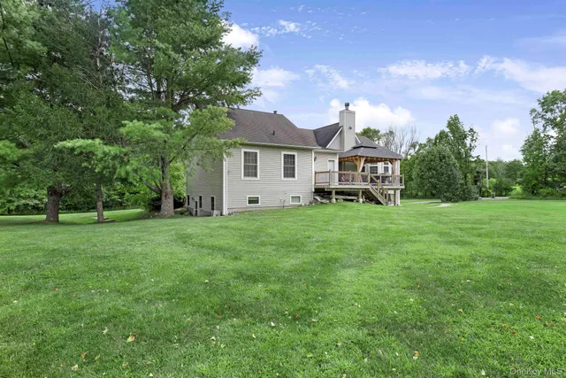 a view of a house with a big yard and large trees