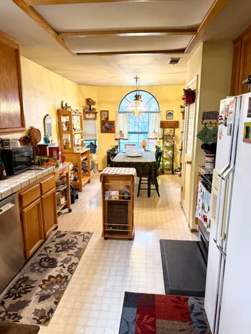 a living room with stainless steel appliances furniture a rug and a kitchen view