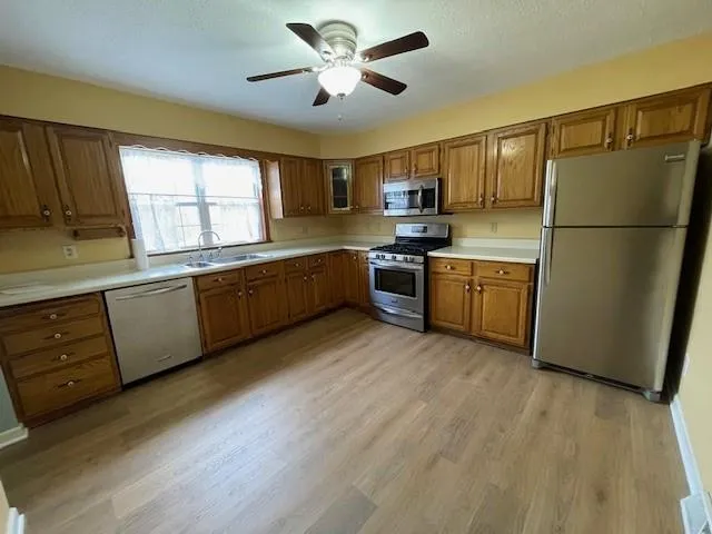 a kitchen with stainless steel appliances granite countertop a refrigerator a sink dishwasher a stove and a refrigerator