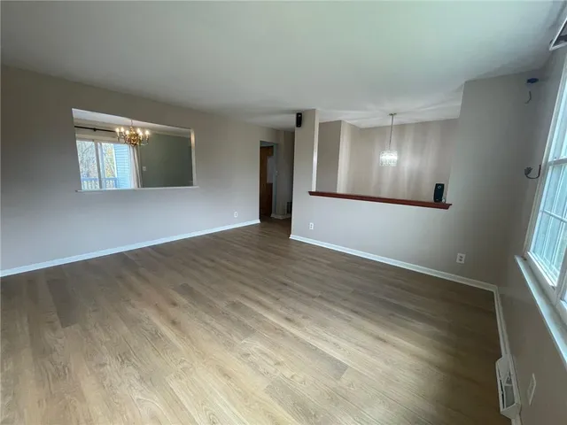 a view of an empty room with wooden floor and windows